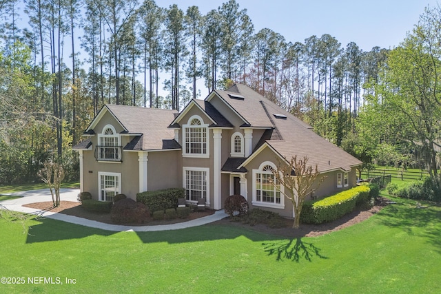 view of front of property with stucco siding, a front yard, and fence