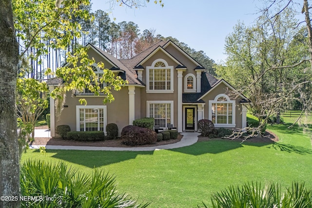 traditional-style home featuring a front lawn and stucco siding