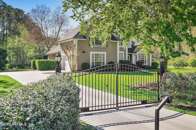 view of front of home featuring a front yard, a gate, an attached garage, stucco siding, and concrete driveway