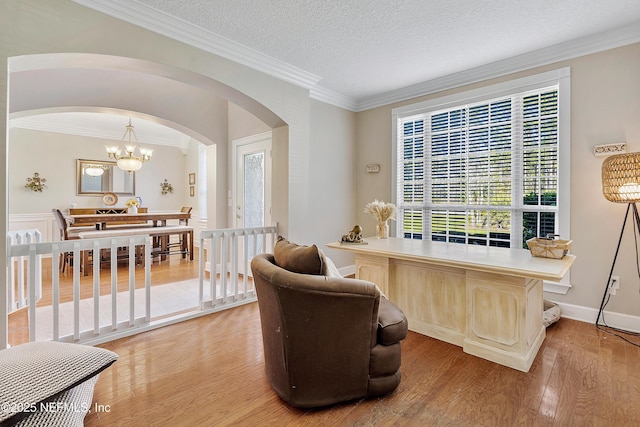 home office with a textured ceiling, arched walkways, light wood finished floors, and ornamental molding