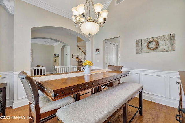 dining space with crown molding, visible vents, light wood finished floors, and wainscoting