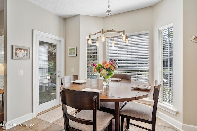 dining area with a notable chandelier, baseboards, and a textured ceiling