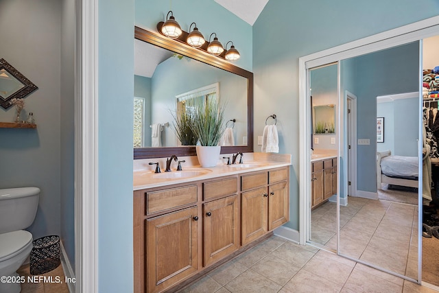 full bathroom with double vanity, tile patterned floors, toilet, and a sink