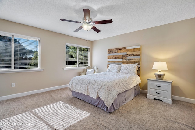 bedroom featuring ceiling fan, light colored carpet, baseboards, and a textured ceiling