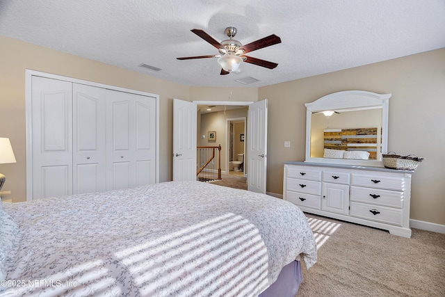 bedroom with visible vents, attic access, a closet, a textured ceiling, and light carpet