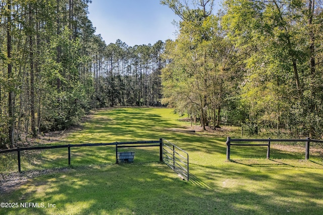 surrounding community with a lawn, fence, and a forest view