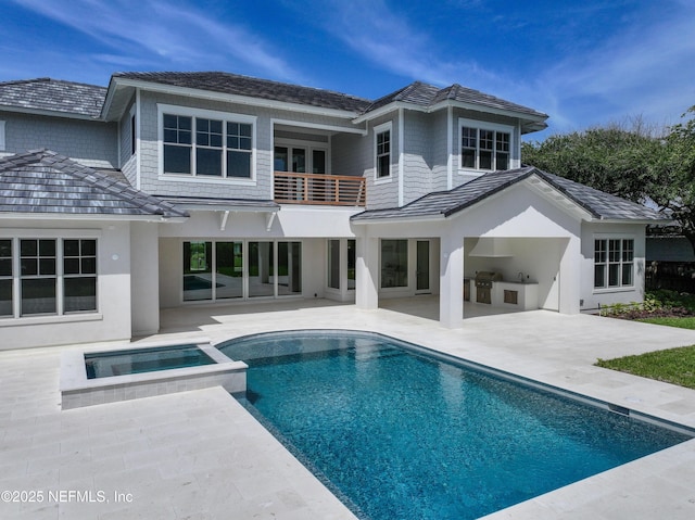 rear view of property featuring a pool with connected hot tub, a patio area, area for grilling, a balcony, and stucco siding