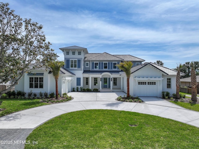view of front of home with a front lawn, stucco siding, curved driveway, and a garage