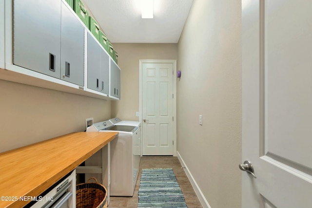 laundry area with washer and clothes dryer, cabinet space, baseboards, and wood finished floors