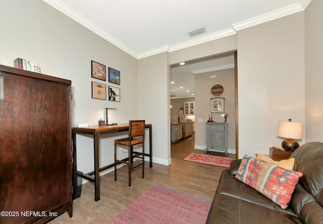 office space featuring visible vents, light wood-style flooring, ornamental molding, a sink, and baseboards