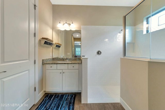 full bathroom featuring baseboards, walk in shower, wood finished floors, and vanity