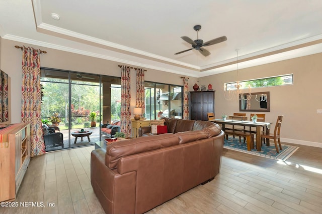 living room featuring a raised ceiling, crown molding, and wood finished floors