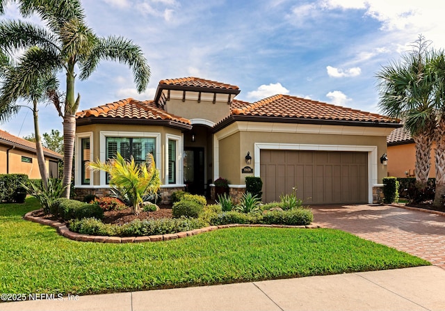 mediterranean / spanish house featuring stucco siding, a front lawn, decorative driveway, stone siding, and a garage