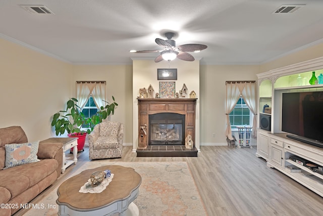 living area with visible vents, light wood-style floors, and ornamental molding