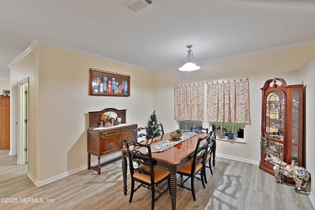 dining room featuring crown molding, light wood-style flooring, baseboards, and visible vents