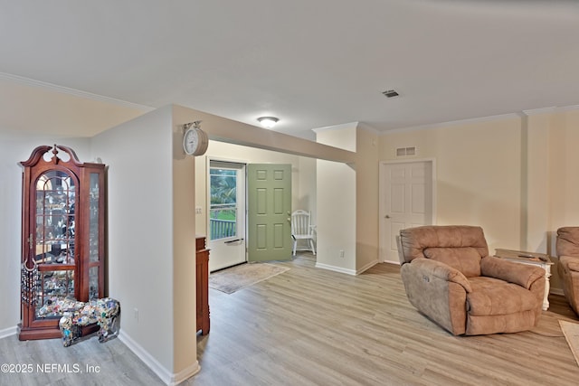 sitting room with visible vents, baseboards, light wood-style flooring, and crown molding