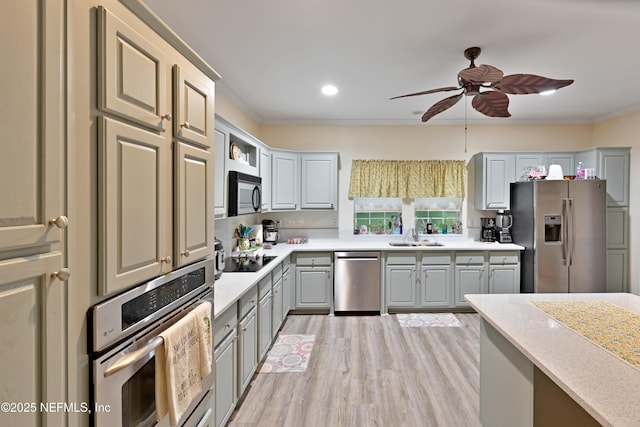 kitchen featuring light wood-style flooring, ornamental molding, gray cabinets, appliances with stainless steel finishes, and light countertops