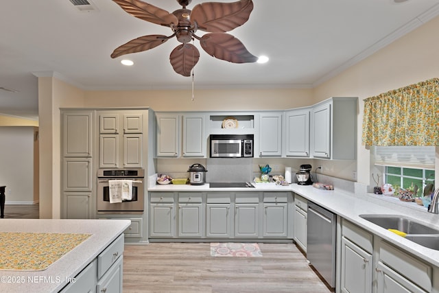 kitchen with crown molding, light countertops, appliances with stainless steel finishes, and a sink