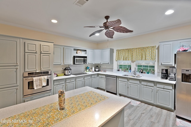 kitchen featuring visible vents, ornamental molding, a sink, appliances with stainless steel finishes, and light countertops