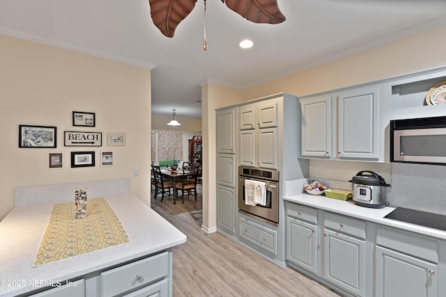 kitchen with gray cabinetry, light wood-type flooring, light countertops, ornamental molding, and stainless steel appliances