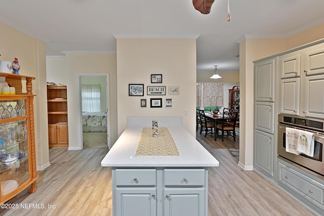 kitchen featuring a peninsula, light wood-style flooring, gray cabinets, ornamental molding, and stainless steel oven