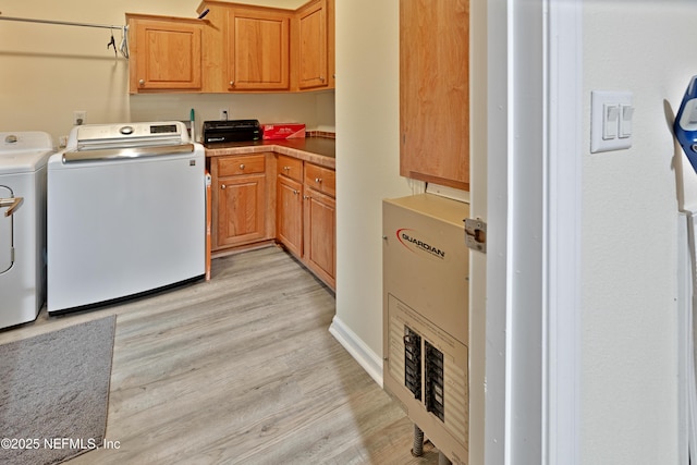 laundry area with cabinet space, light wood-style floors, and washing machine and clothes dryer