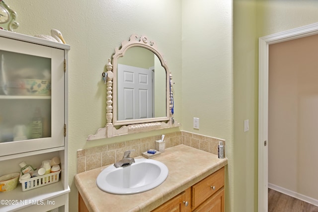 bathroom featuring tasteful backsplash, wood finished floors, and vanity