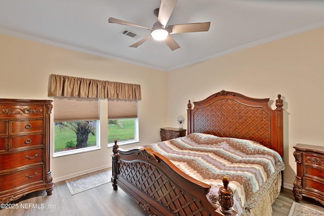 bedroom with a ceiling fan, crown molding, visible vents, and light wood-type flooring