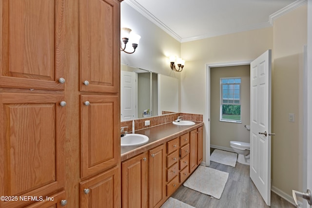 full bath featuring ornamental molding, toilet, double vanity, and a sink