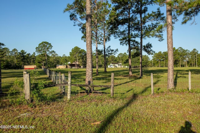 view of gate with a rural view, fence, and a lawn