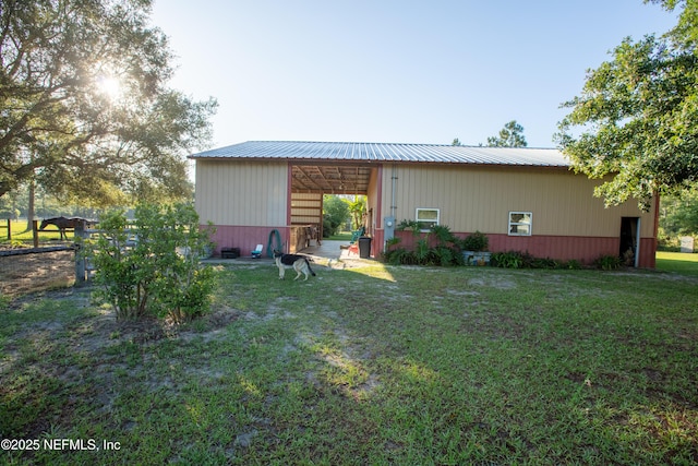 rear view of property with metal roof, an outbuilding, and a lawn