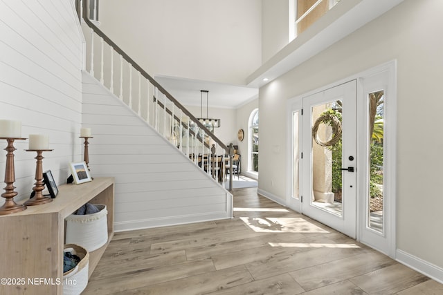 foyer entrance featuring stairway, baseboards, wood finished floors, and a towering ceiling