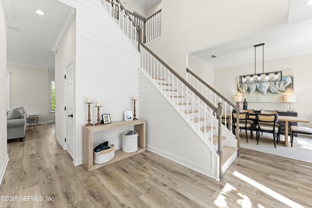 stairway with a high ceiling, crown molding, baseboards, and wood finished floors