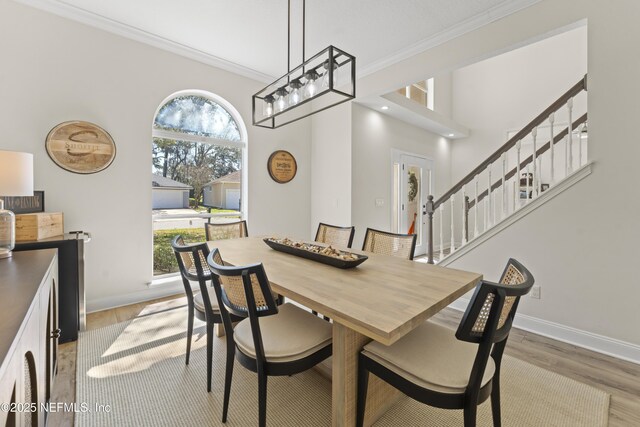 dining room featuring baseboards, wood finished floors, ornamental molding, and stairs