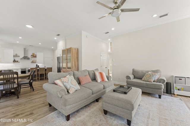 living area featuring a ceiling fan, visible vents, recessed lighting, crown molding, and light wood-type flooring