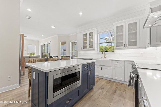 kitchen featuring white cabinetry, under cabinet range hood, appliances with stainless steel finishes, and a sink