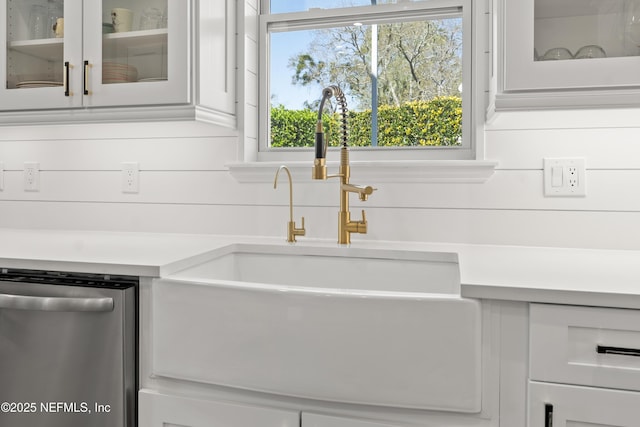 details with dishwasher, light countertops, glass insert cabinets, and a sink