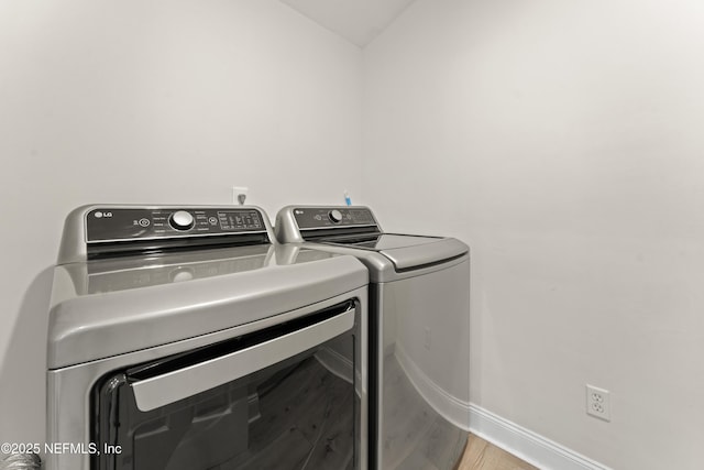 laundry room featuring baseboards, wood finished floors, laundry area, and washing machine and clothes dryer