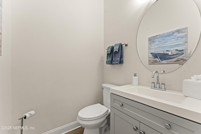 half bath with vanity, toilet, and baseboards