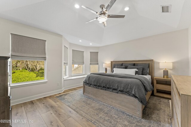 bedroom featuring visible vents, a raised ceiling, wood finished floors, recessed lighting, and baseboards