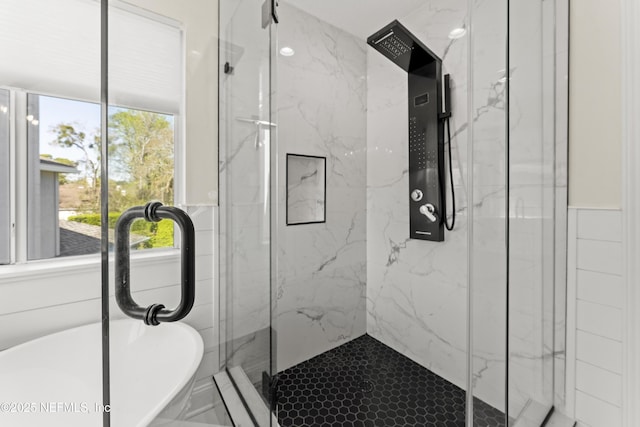 full bathroom featuring a sink, a marble finish shower, and a soaking tub