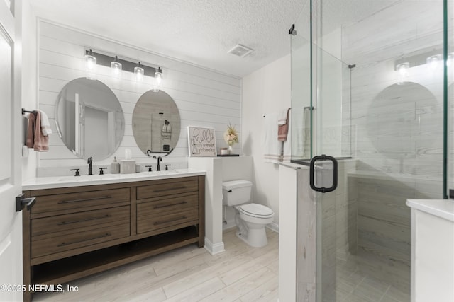 full bath with visible vents, a textured ceiling, wood finished floors, and a sink