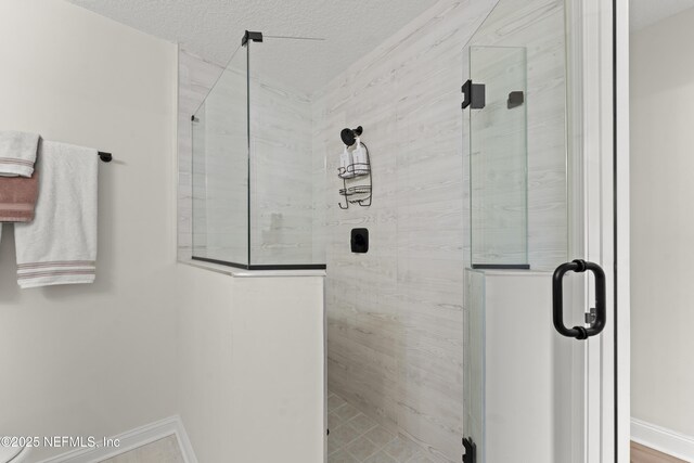 bathroom featuring baseboards, a stall shower, and a textured ceiling