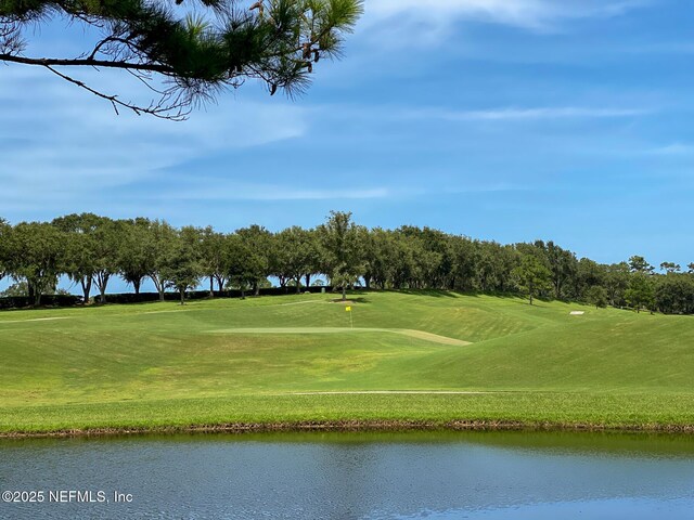 view of community featuring a lawn, golf course view, and a water view