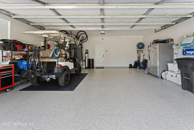 garage with a garage door opener and stainless steel fridge