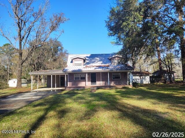 farmhouse with driveway, an attached carport, covered porch, and a front yard