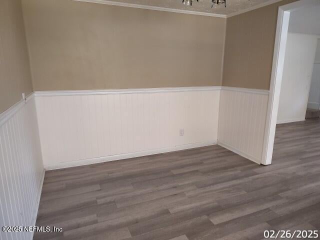 unfurnished room with a wainscoted wall, dark wood-type flooring, and an inviting chandelier