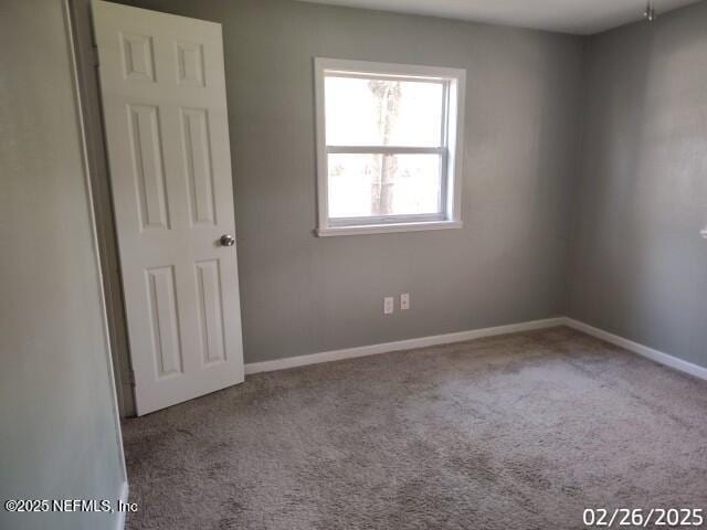 carpeted empty room featuring baseboards