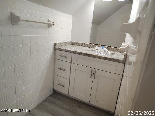 bathroom featuring vanity, tile walls, and wood finished floors