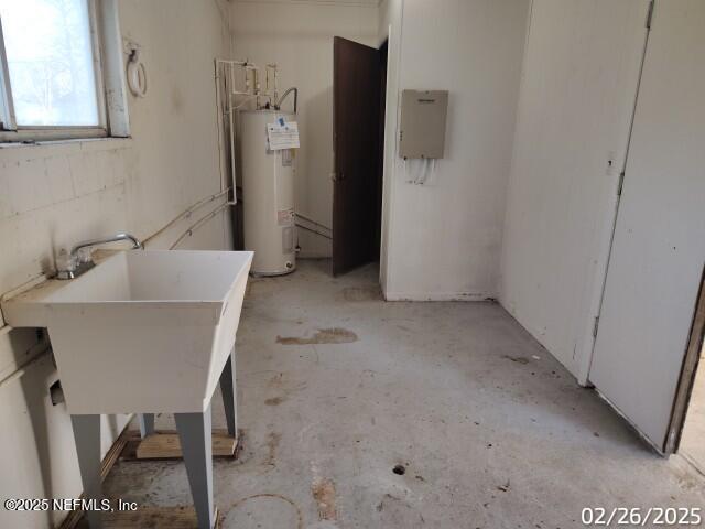 interior space featuring water heater, concrete flooring, and a sink